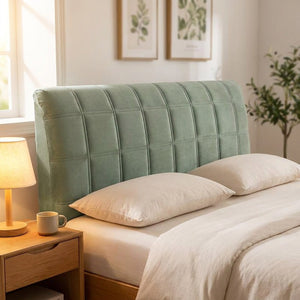 Housse de tête de lit matelassée en velours vert sauge installée sur un lit dans une chambre lumineuse
