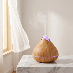 Diffuseur bois clair brume sur surface marbre devant fenêtre lumineuse