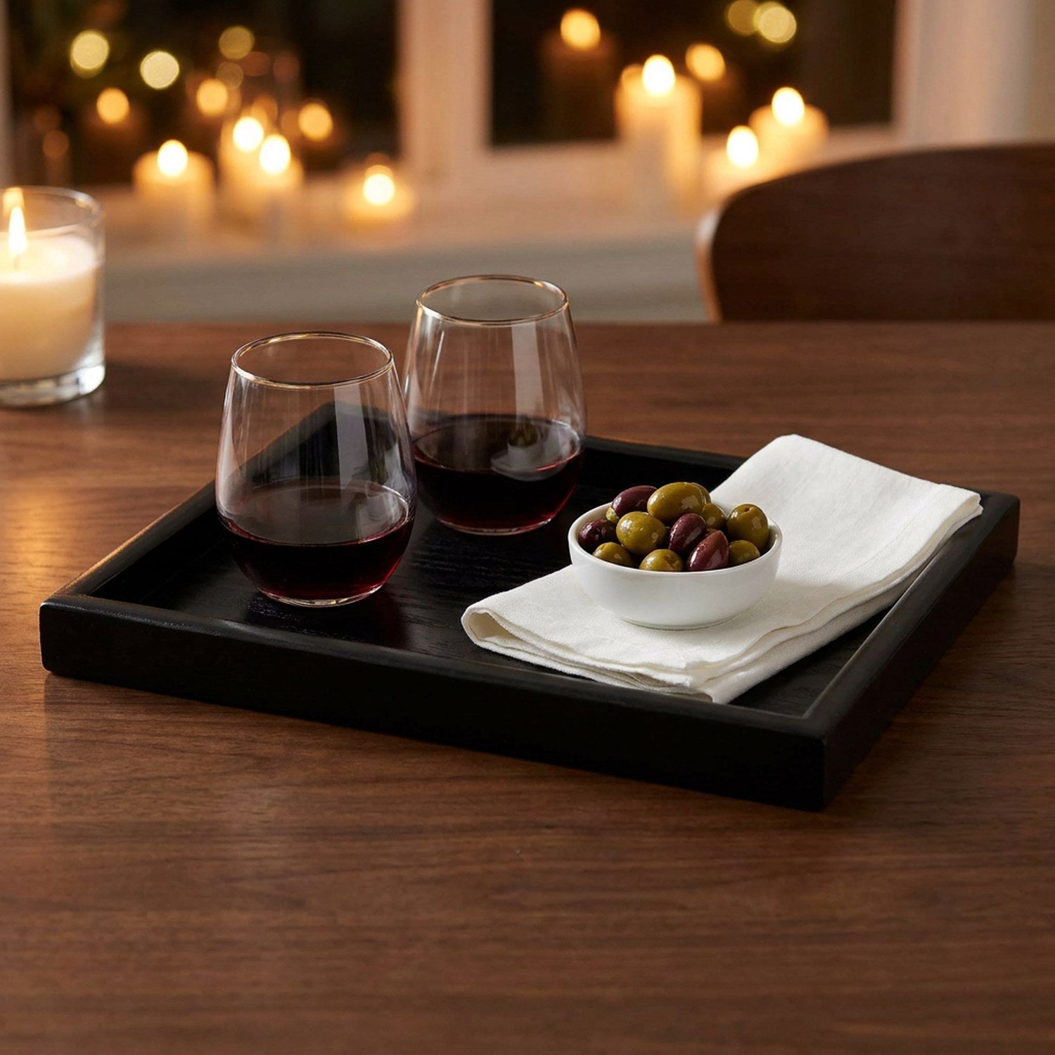 Plateau de service bois noir sur table bois avec verres à vin et olives