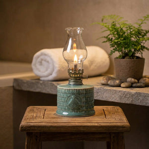 Lampe à pétrole allumée sur un tabouret dans une salle de bain zen avec plante