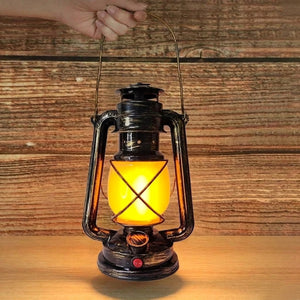 Lampe rétro tenue à la main par sa poignée devant un mur en bois