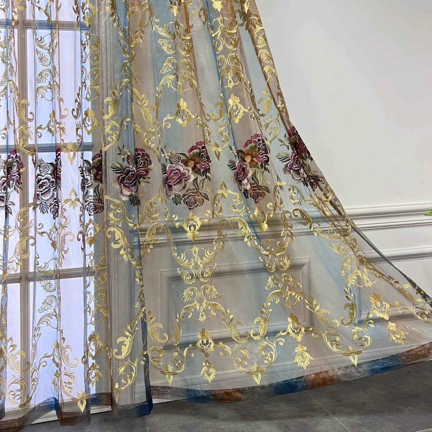 Rideau voilage tulle drapé devant une porte vitrée avec broderie florale dorée