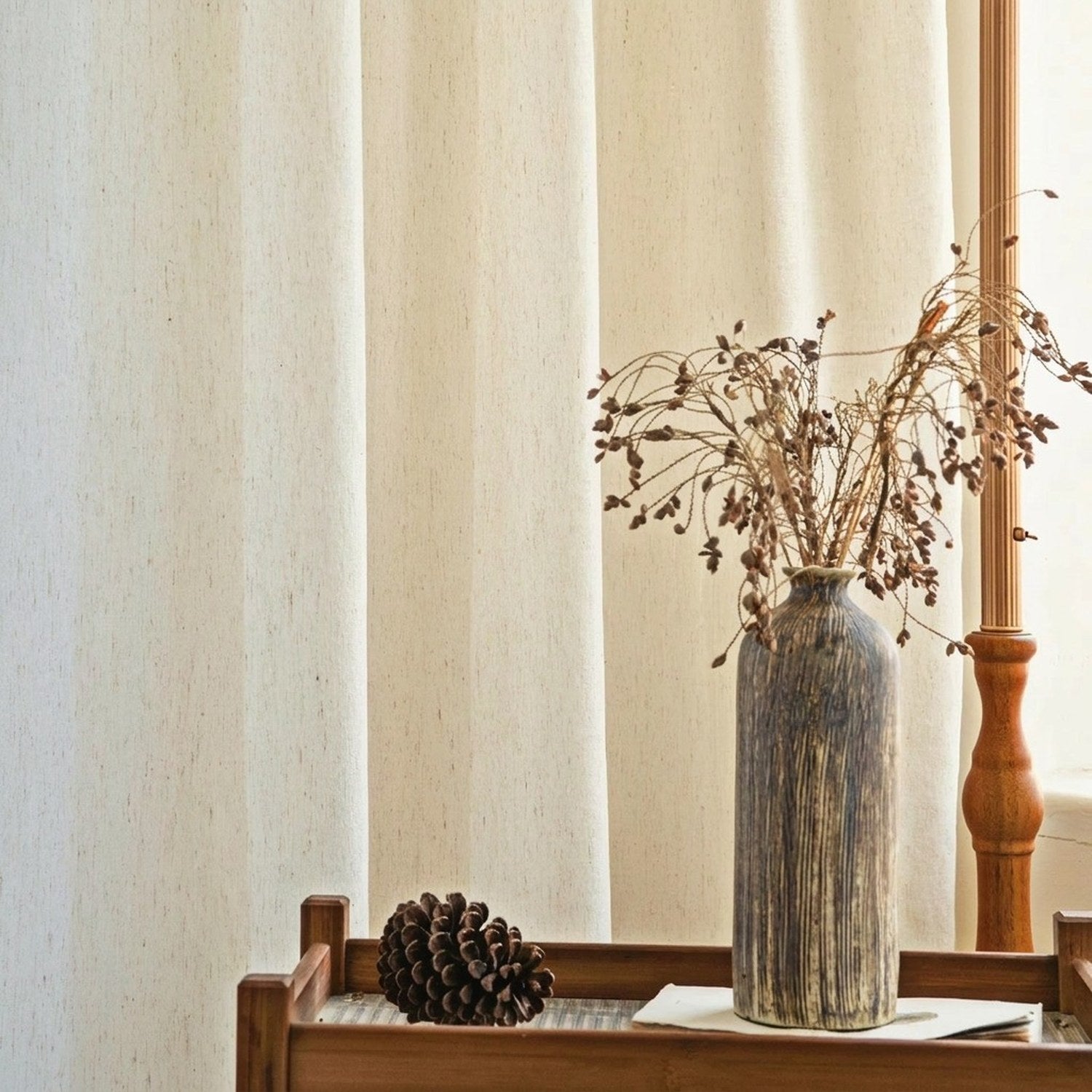 Voilage effet lin près d'une console en bois avec vase et branches séchées