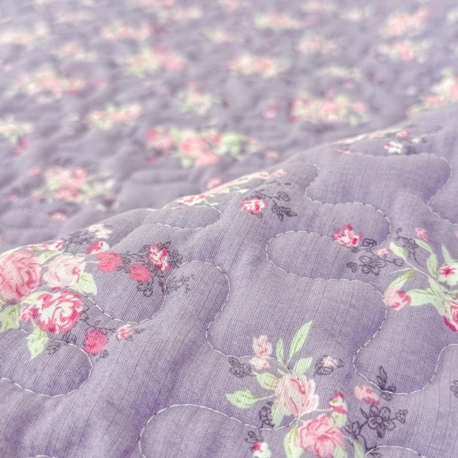 Gros plan sur le tissu matelassé à motif de roses du couvre-lit violet