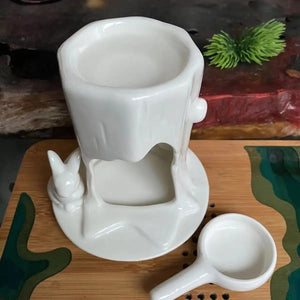 Brûleur à huile céramique lapin avec coupelle accessoire posée à côté sur table en bois