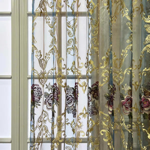 Rideau voilage tulle brodé de fleurs devant une fenêtre à petits carreaux