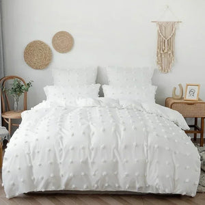 Parure de lit blanche à pompons sur un lit dans une chambre bohème avec macramé mural