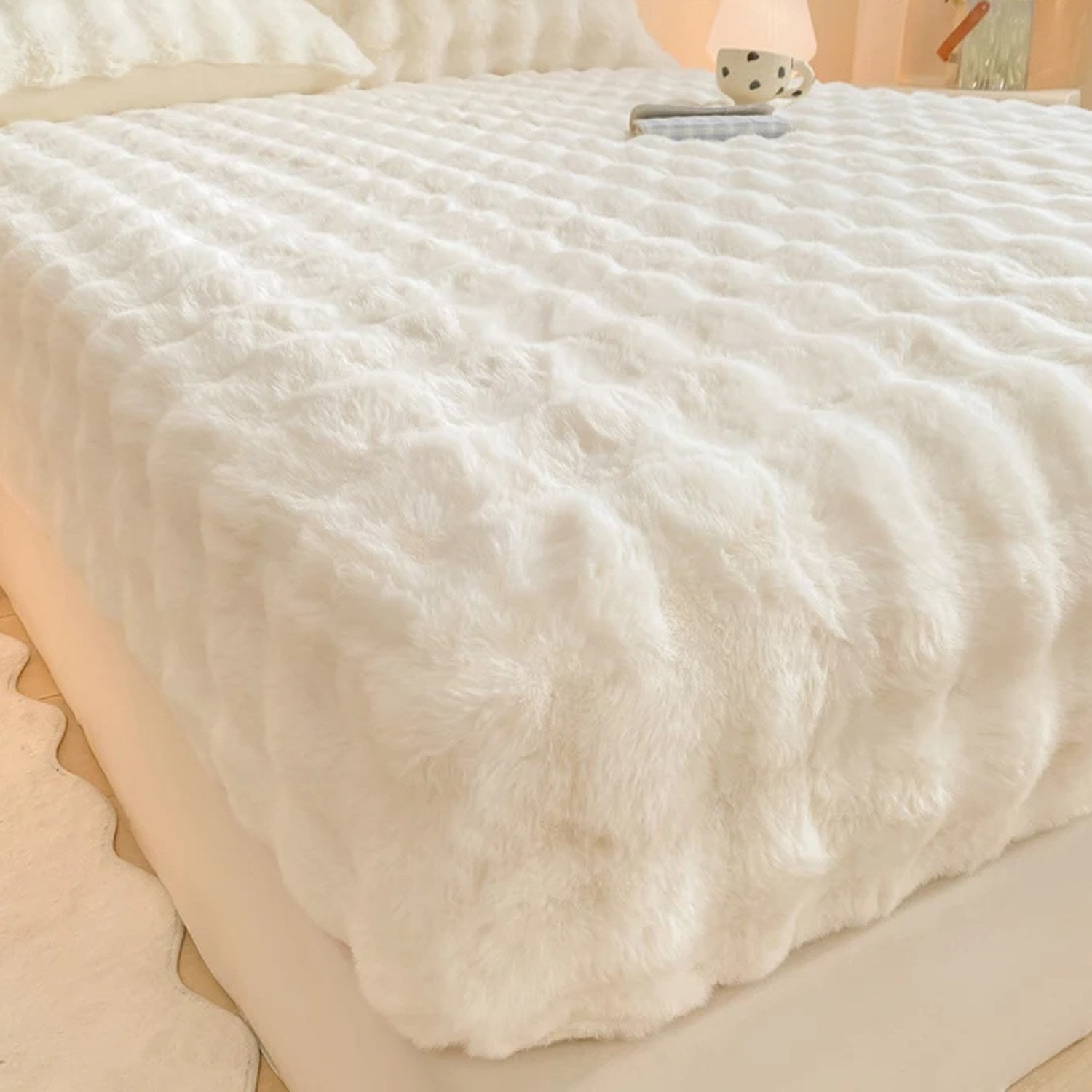 Drap-housse en peluche polaire blanche moelleuse installé sur un lit dans une chambre lumineuse