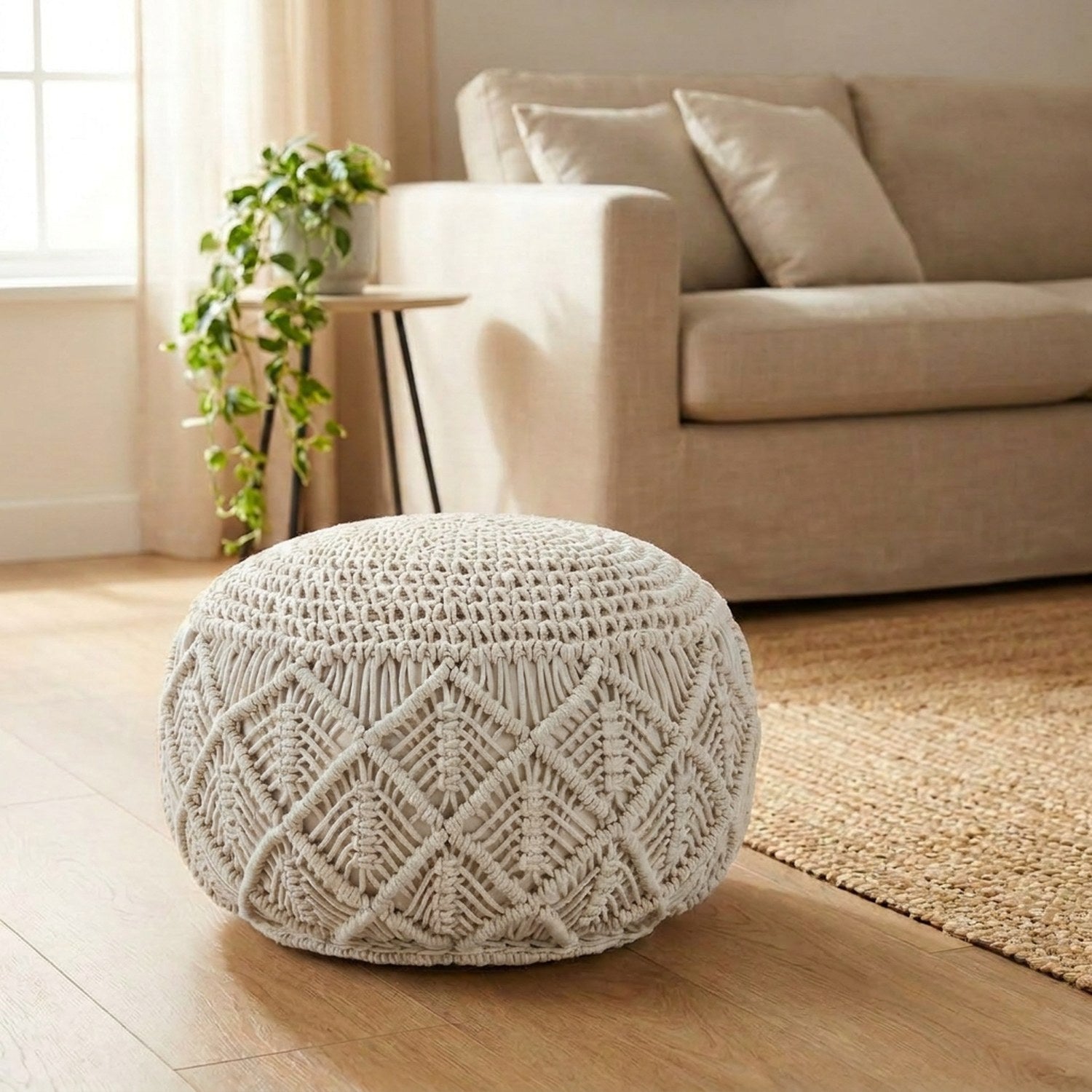 Pouf en macramé rond coloris ivoire posé sur un sol clair dans un salon chaleureux