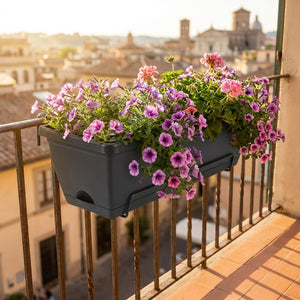 Jardinière de balcon noire avec pétunias roses sur garde-corps en fer forgé