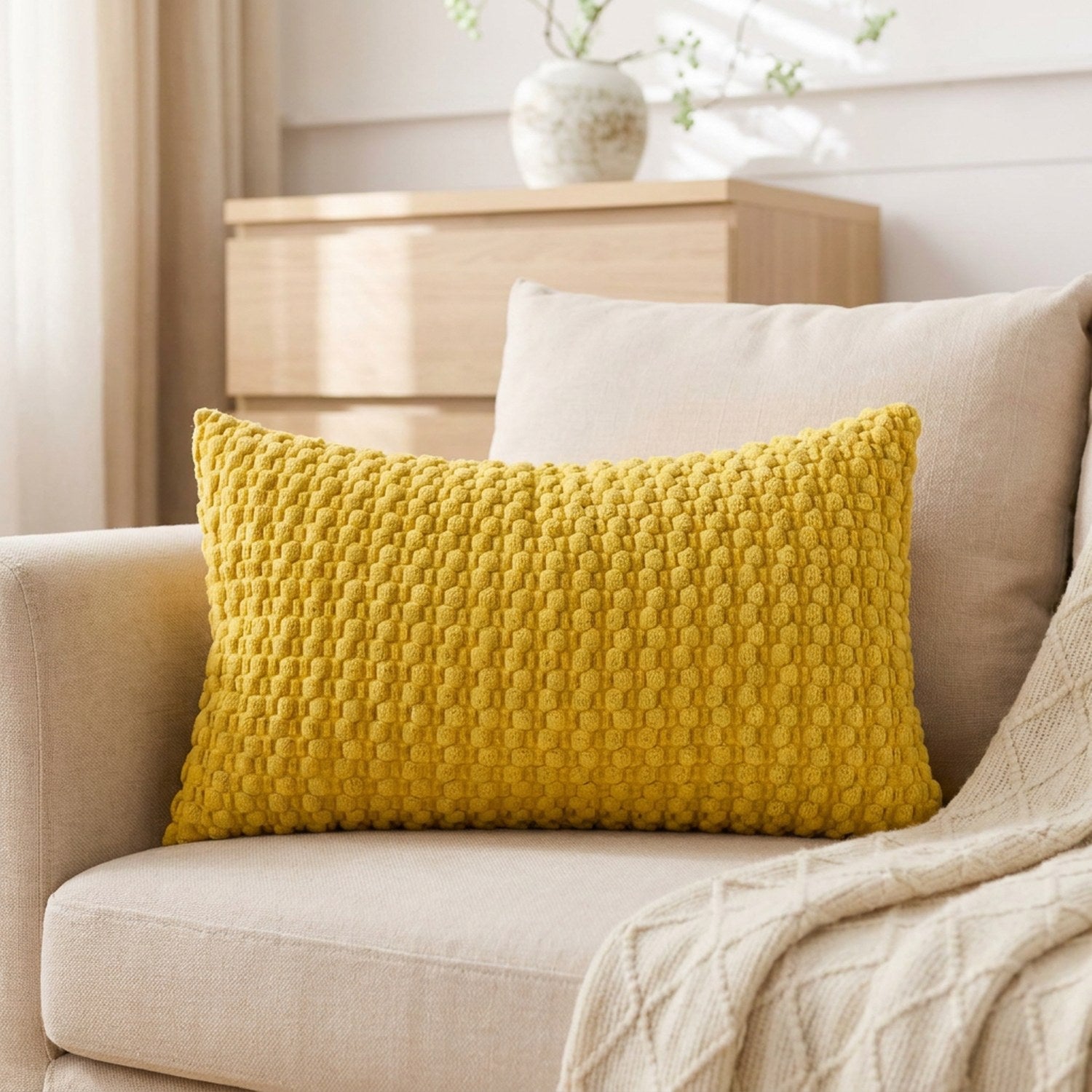 housse de coussin rectangulaire en maille texturée jaune moutarde sur un canapé en lin