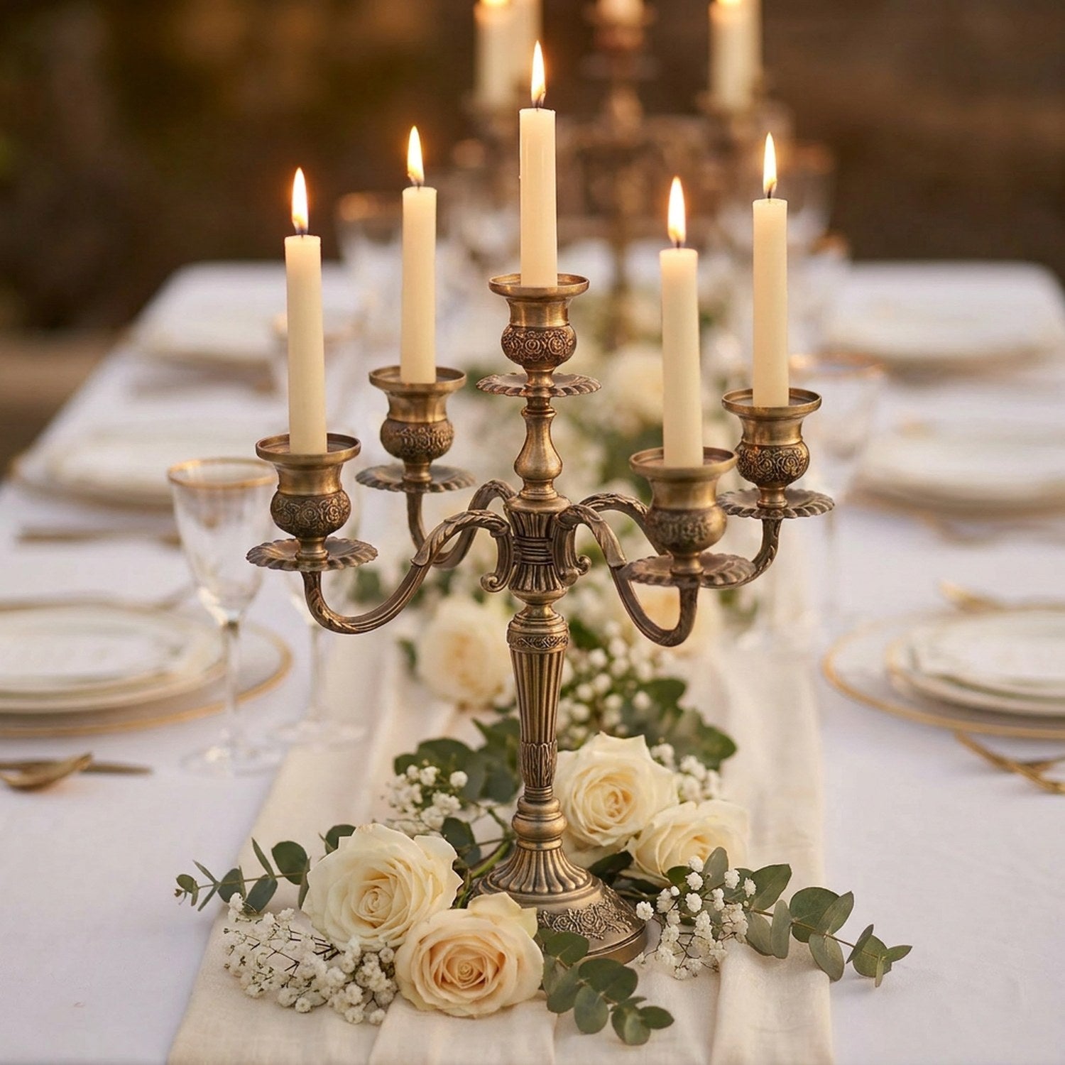 Chandelier en métal bronze allumé en centre de table de mariage avec roses blanches et eucalyptus