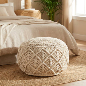 Pouf rond en macramé au pied d'un lit dans une chambre bohème lumineuse