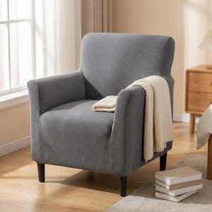 Fauteuil housse grise dans une chambre avec un plaid écru sur l'accoudoir