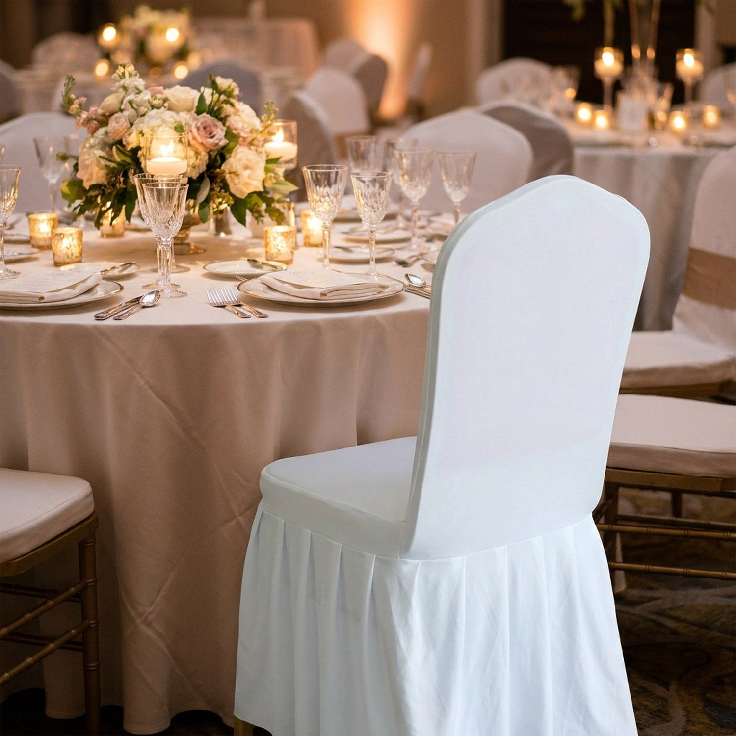 Chaise habillée d'une housse blanche à une table de mariage dressée avec bougies