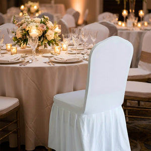 Chaise habillée d'une housse blanche à une table de mariage dressée avec bougies