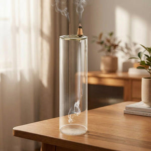 Porte-encens en verre sur un bureau près d'une fenêtre lumineuse