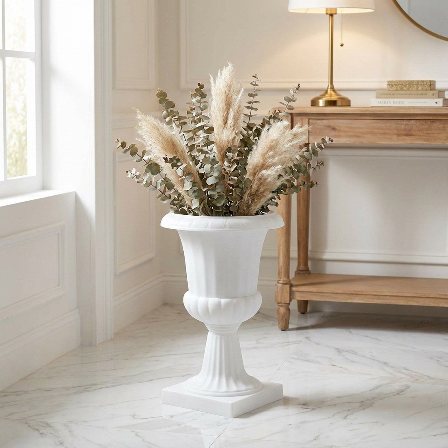 Vase médicis blanc garni de pampa et d'eucalyptus dans une entrée lumineuse