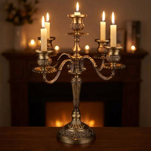 Chandelier en métal bronze aux bougies allumées posé sur un manteau de cheminée