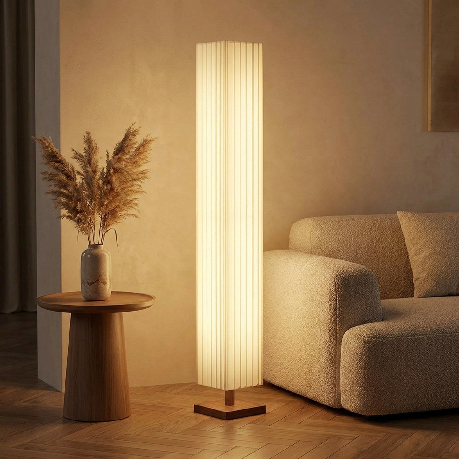 Lampadaire allumé près d'un canapé beige et d'un vase de pampa dans un salon
