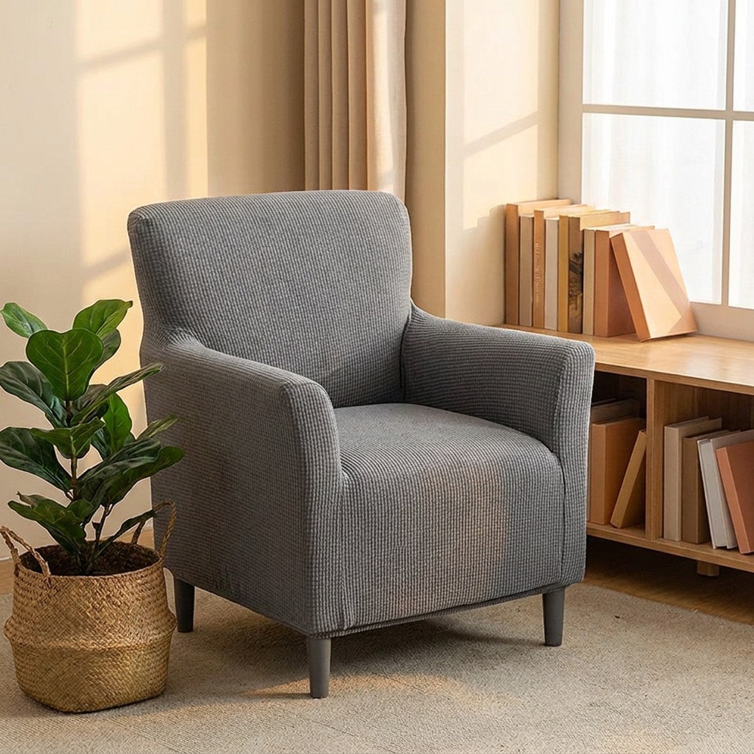 Fauteuil housse grise près d'une bibliothèque basse en bois et une plante