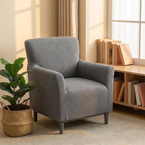 Fauteuil housse grise près d'une bibliothèque basse en bois et une plante
