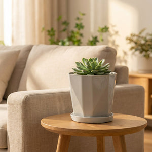 Cache-pot gris à facettes sur une table d'appoint près d'un canapé en lin