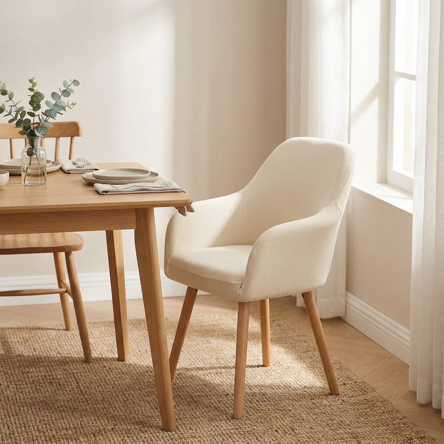 Housse de fauteuil écru sur une chaise à accoudoirs dans une salle à manger lumineuse