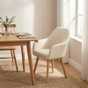 Housse de fauteuil écru sur une chaise à accoudoirs dans une salle à manger lumineuse