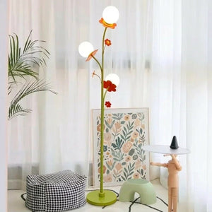 Lampadaire floral 3 globes allumé salon parquet plante verte