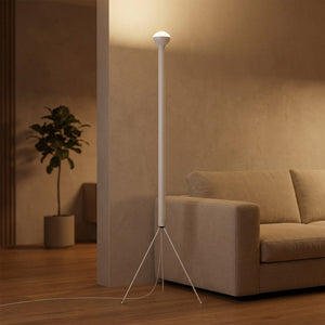 Lampadaire trépied blanc allumé dans un salon chaleureux