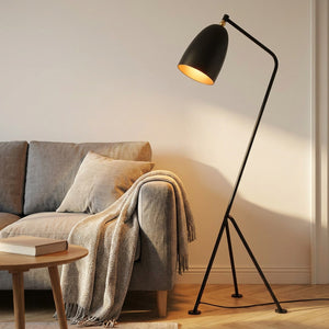 Lampadaire grasshopper noir posé près d'un canapé gris dans un salon scandinave
