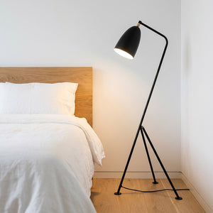Lampadaire trépied grasshopper dans un coin de chambre à coucher chaleureux