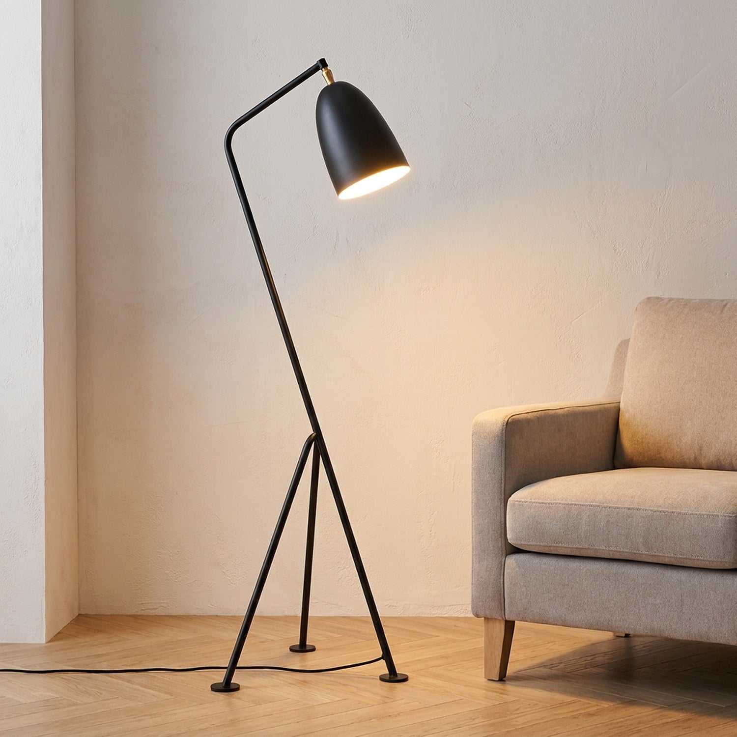 Lampadaire trépied grasshopper en métal allumé dans un salon moderne avec fauteuil