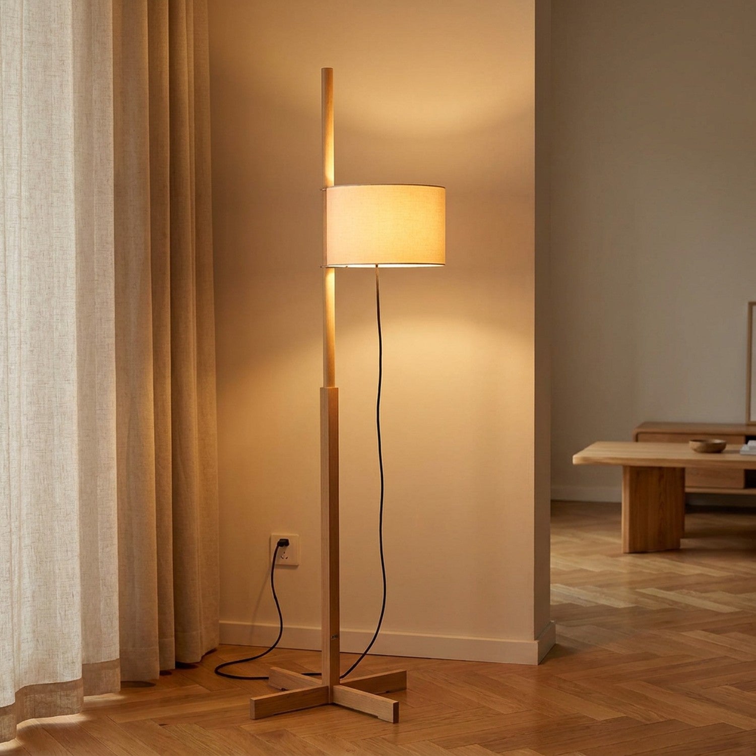 Lampadaire japonais en bois naturel avec abat-jour cylindrique blanc allumé dans un salon japandi