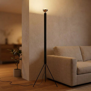 Lampadaire trépied noir allumé dans un salon chaleureux