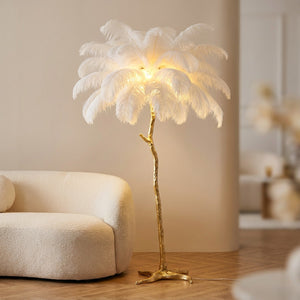 Lampadaire plumes d'autruche blanches effet palmier sur base dorée allumé dans un salon élégant