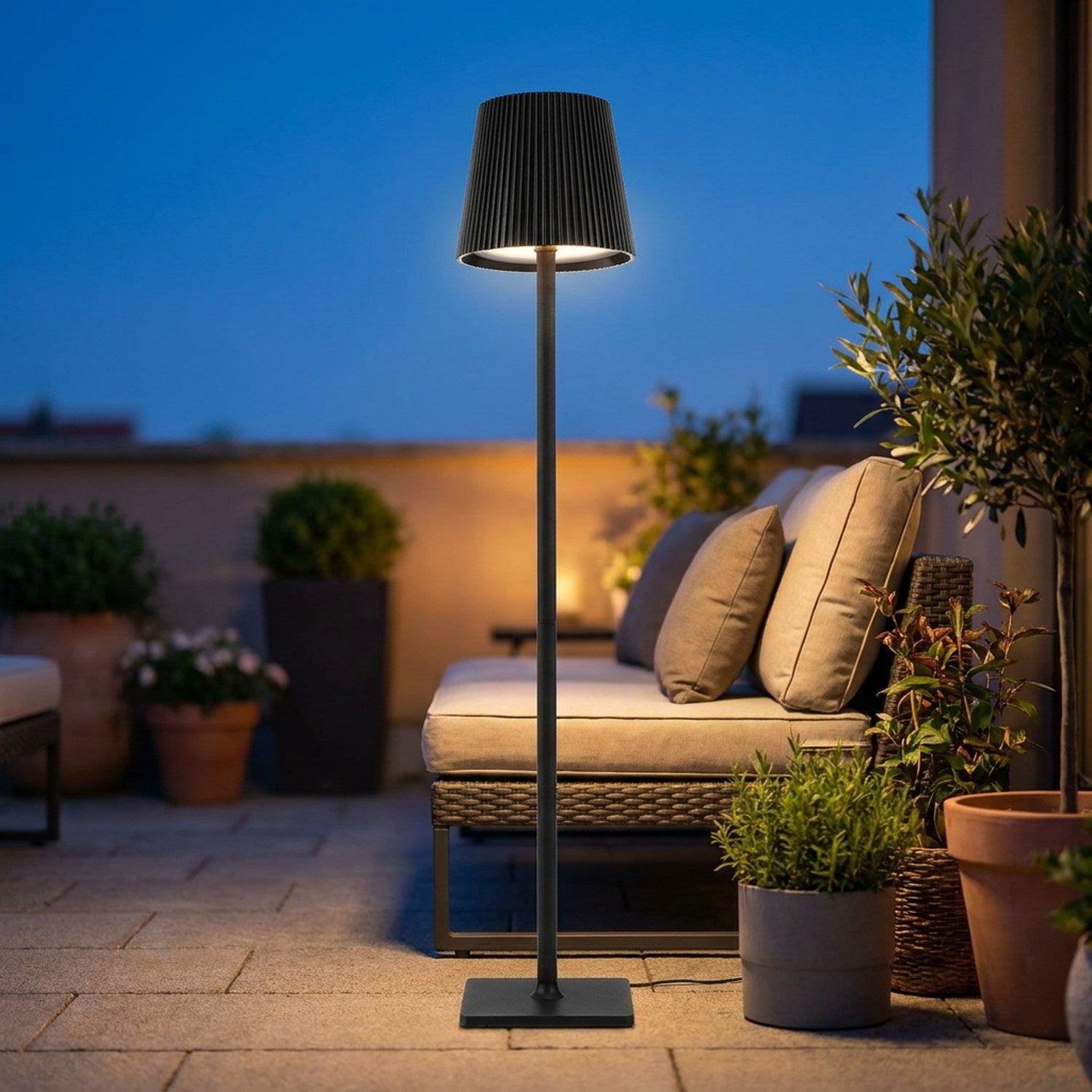 Lampadaire LED noir sans fil allumé sur une terrasse extérieure au crépuscule