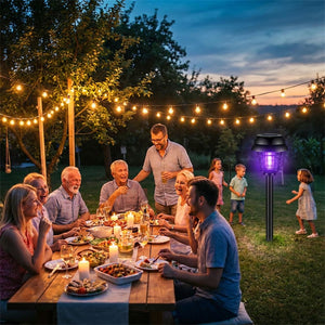 Famille réunie autour d'une table en jardin au crépuscule, lampe solaire UV plantée dans la pelouse