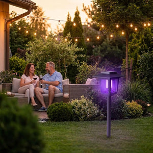 Couple se relaxant en terrasse le soir, lampe anti-moustiques solaire UV allumée dans le jardin