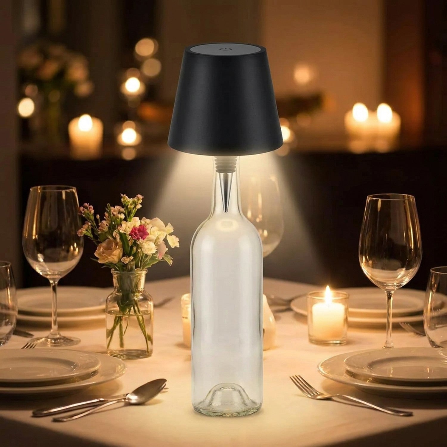 Lampe de table sans fil noire posée sur une bouteille au centre d'une table de dîner aux chandelles