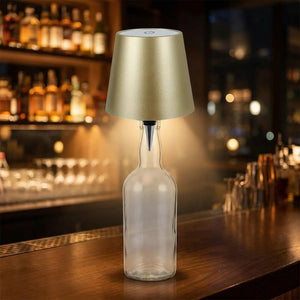 Lampe de table sans fil dorée fixée sur une bouteille en verre diffusant une lumière chaude tamisée