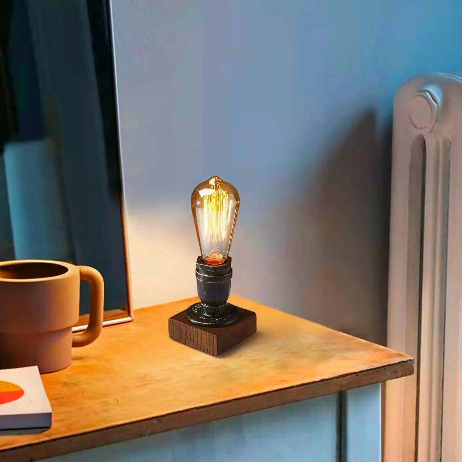 Lampe industrielle allumée sur une table près d'un miroir et d'une tasse