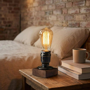 Lampe de chevet industrielle allumée sur une table de nuit près d'un lit