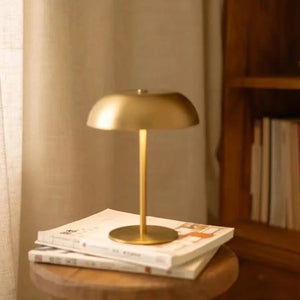 Lampe de chevet champignon dorée posée sur des magazines