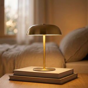 Lampe de chevet champignon dorée posée sur une table de nuit en bois