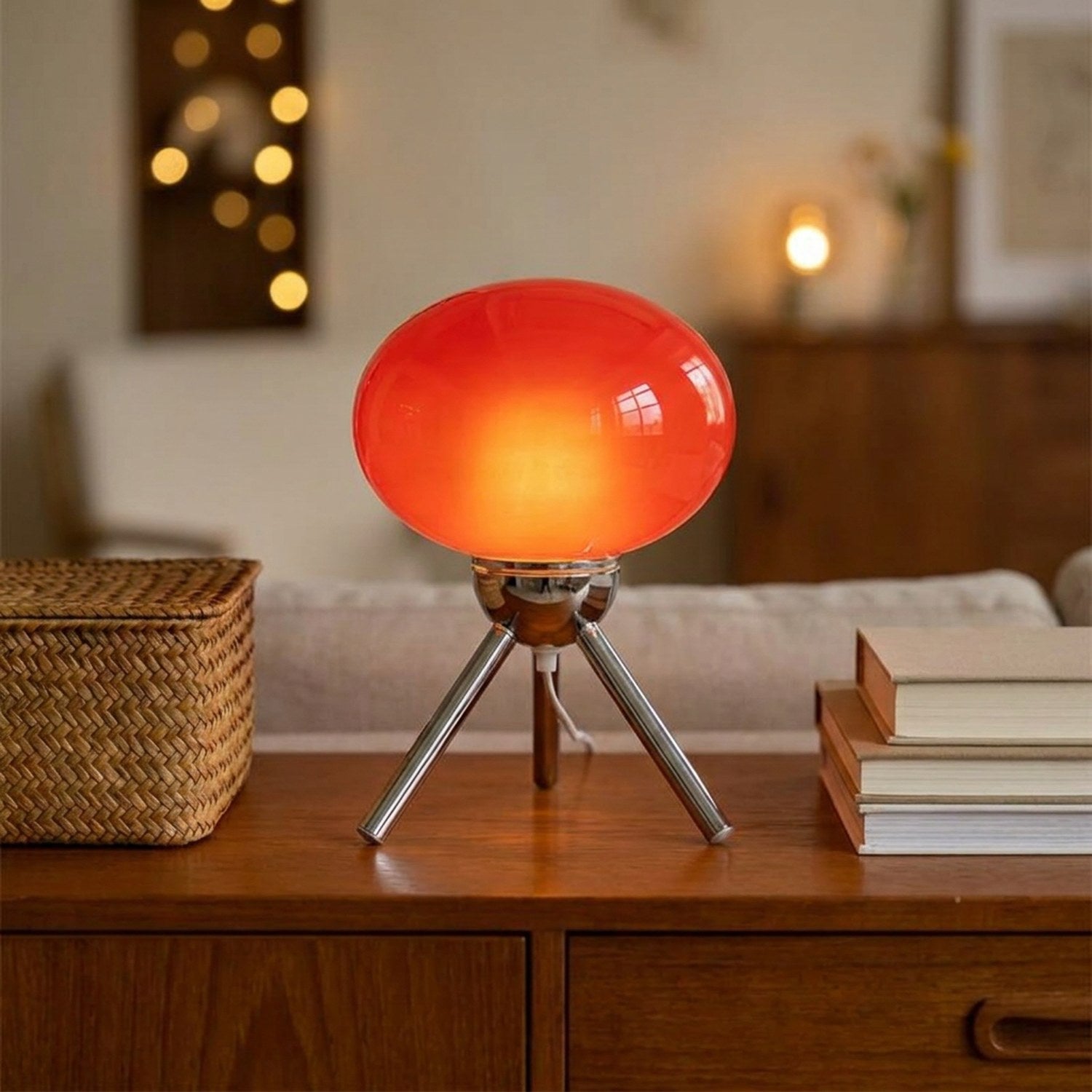 Lampe champignon rouge allumée sur un meuble bas rétro avec livres et panier en osier