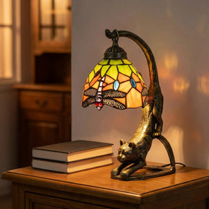 Lampe chat en vitrail façon Tiffany allumée sur une table de chevet en bois