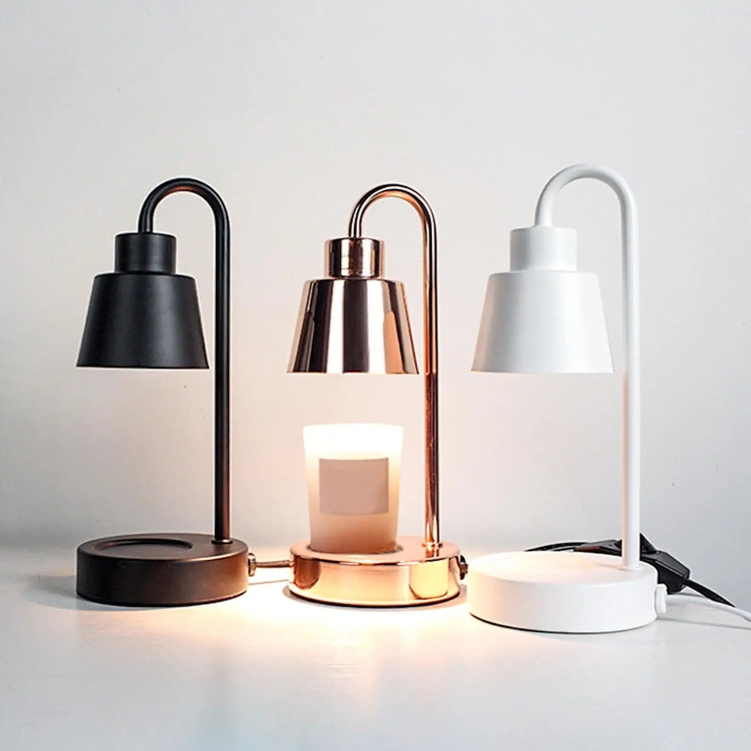 Lampe chauffe-bougie en trois coloris noir doré et blanc allumée avec bougies parfumées