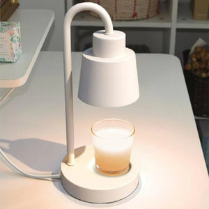 Lampe chauffe-bougie blanche sur un bureau avec bougie parfumée en verre transparent